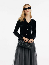 a lady in a black v-neck velvet top and black tulle midi skirt